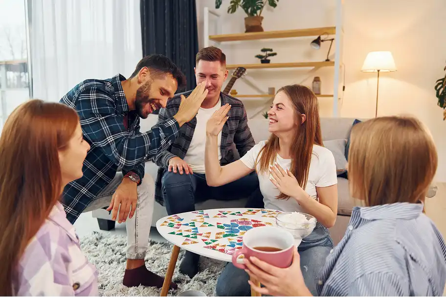 egy baráti társaság, akik társasjátékot játszanak és pacsiznak a nappaliban